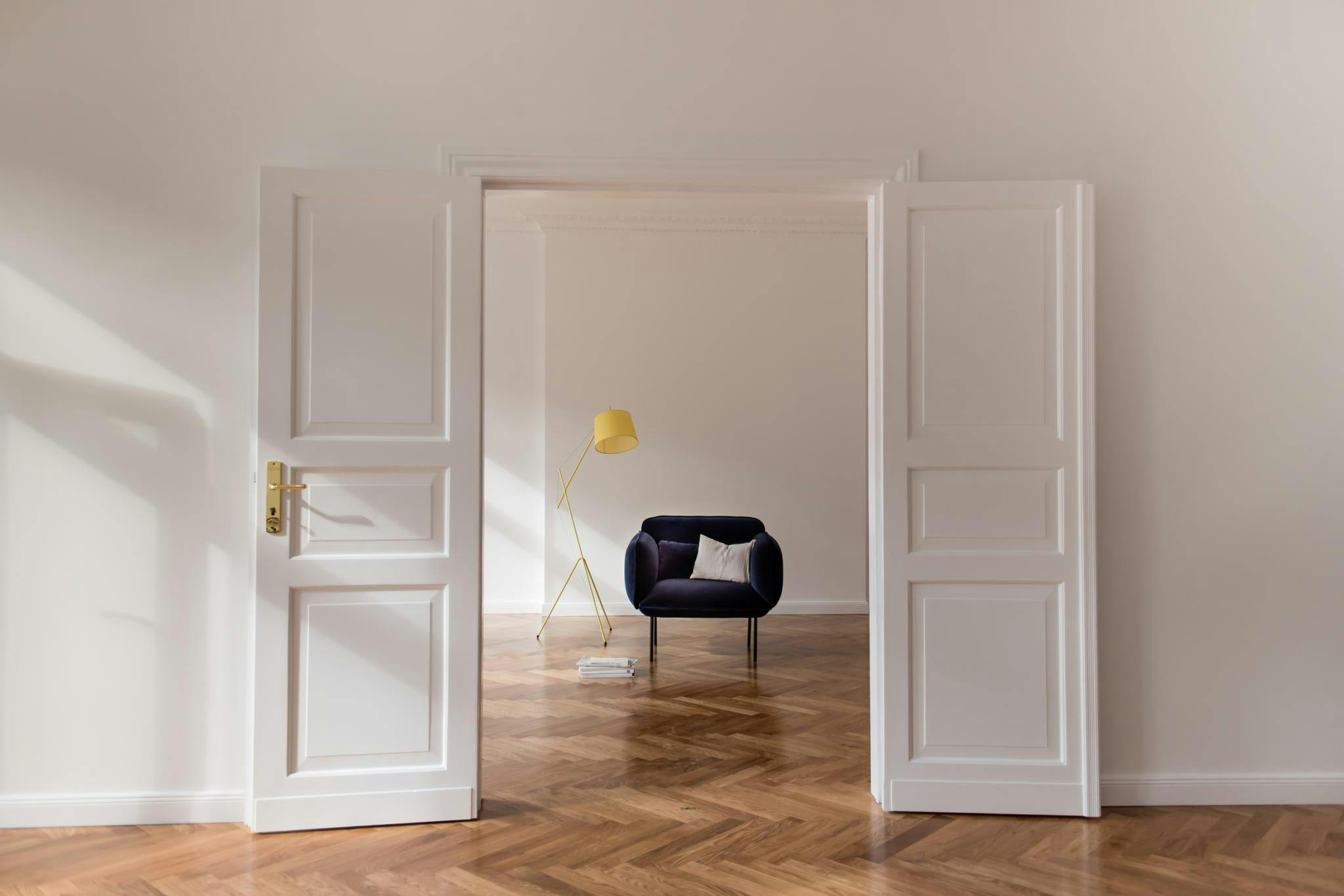 The image features a white doorway with a black chair placed in front of it. The chair is positioned in the center of the room, and it appears to be a comfortable and inviting seating area. The room is empty, with no other furniture or people visible. The doorway is open, revealing a hallway beyond it. The overall atmosphere of the room is calm and serene, with the chair providing a focal point in the otherwise empty space.