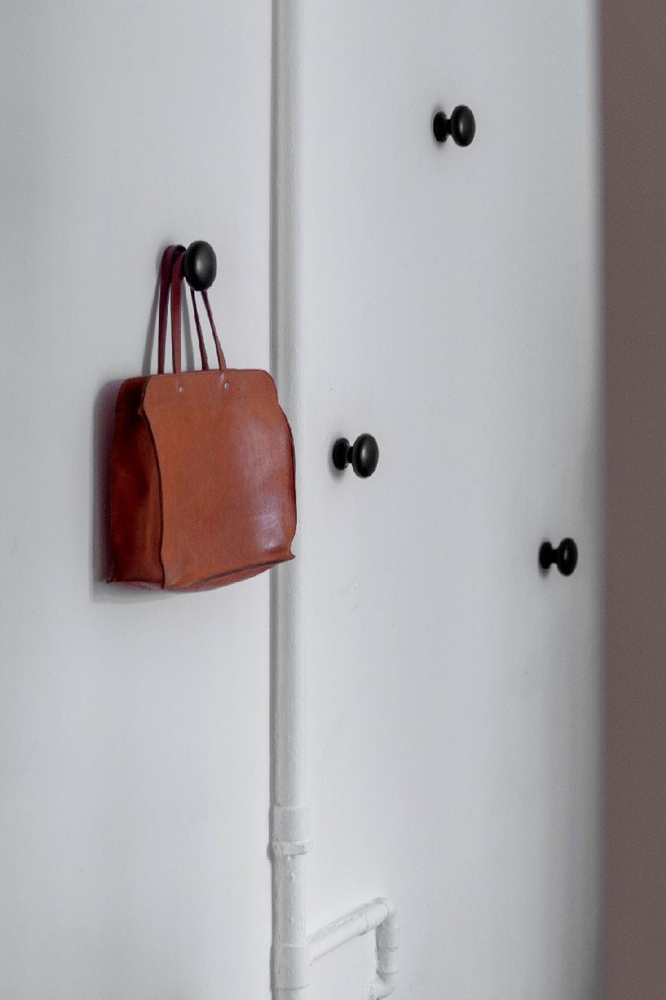 A white door with a brown leather bag hanging on it is shown in a room.