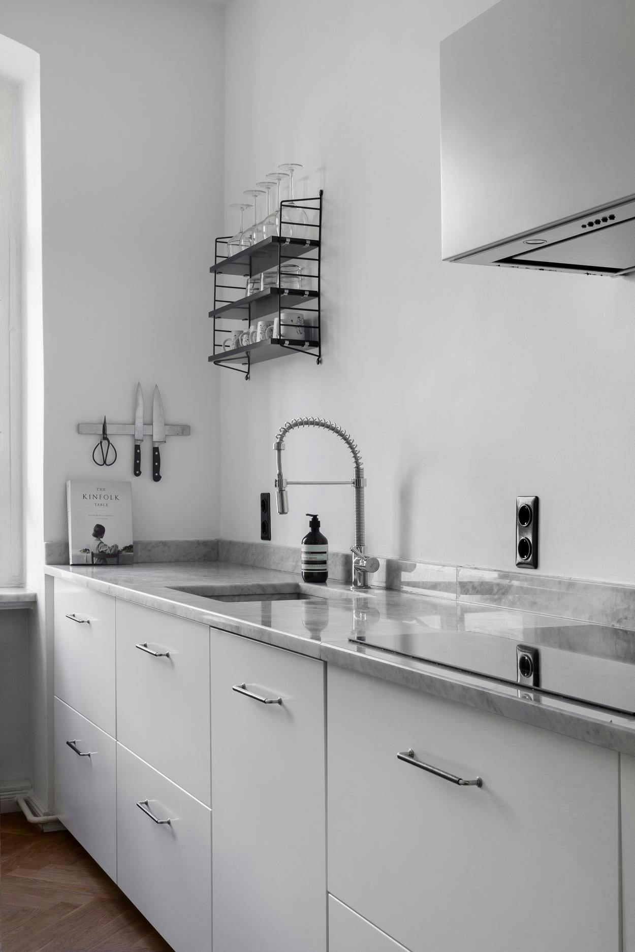 The image features a clean, modern kitchen with white cabinets and a stainless steel sink.