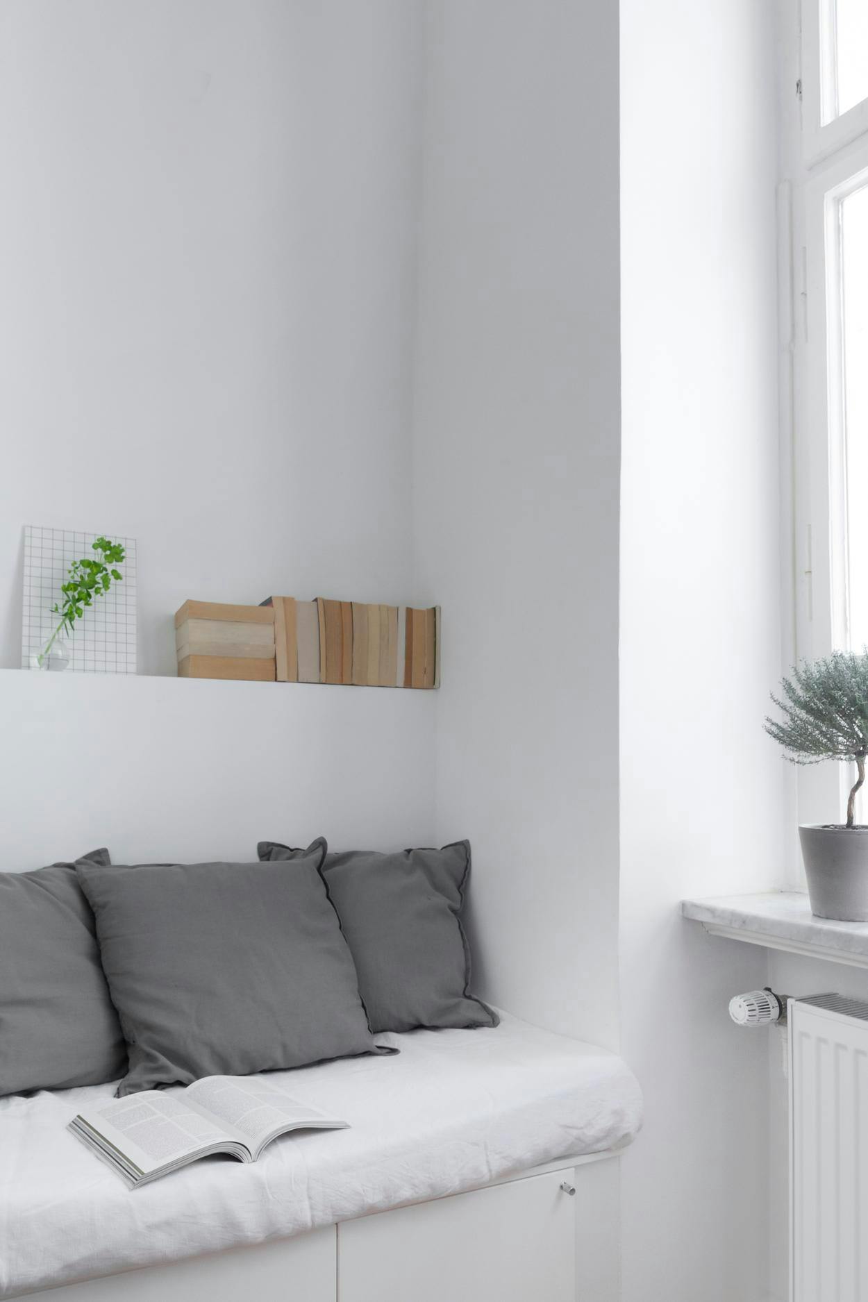 A white bench is placed in a room with a window, and a potted plant is placed next to it.