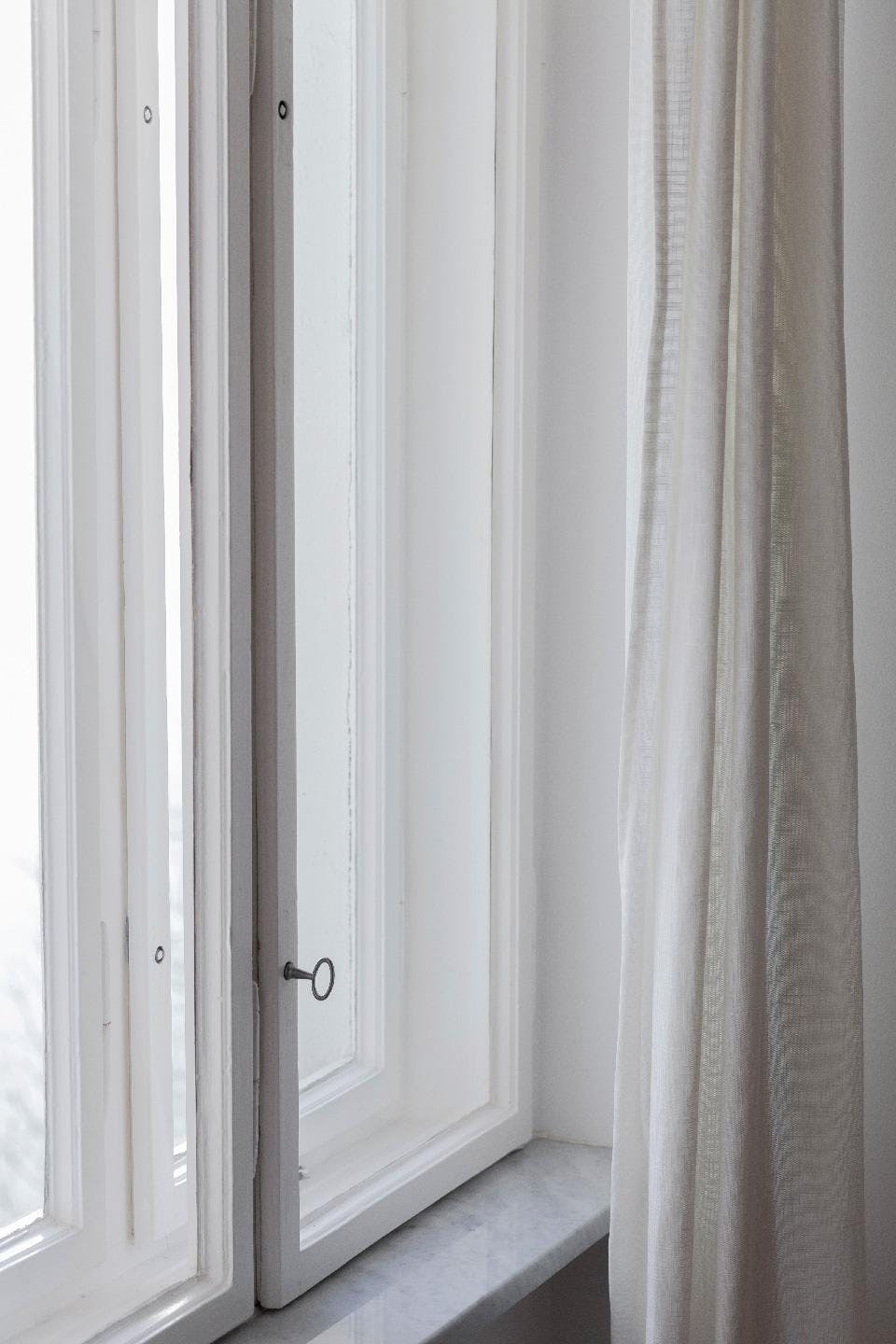A white door is open, revealing a window with a curtain.