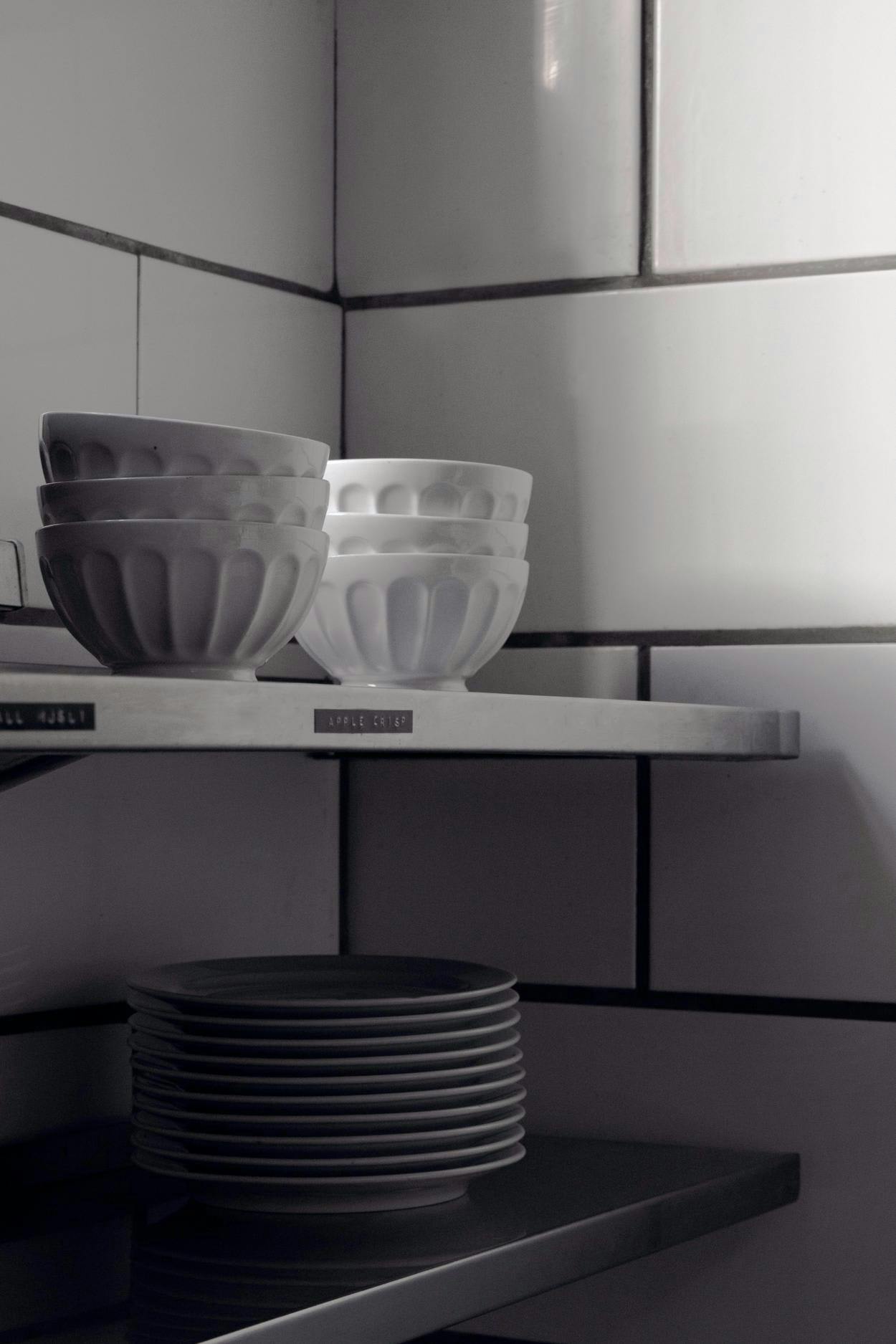 The image features a white kitchen counter with a variety of white bowls and plates arranged on it.