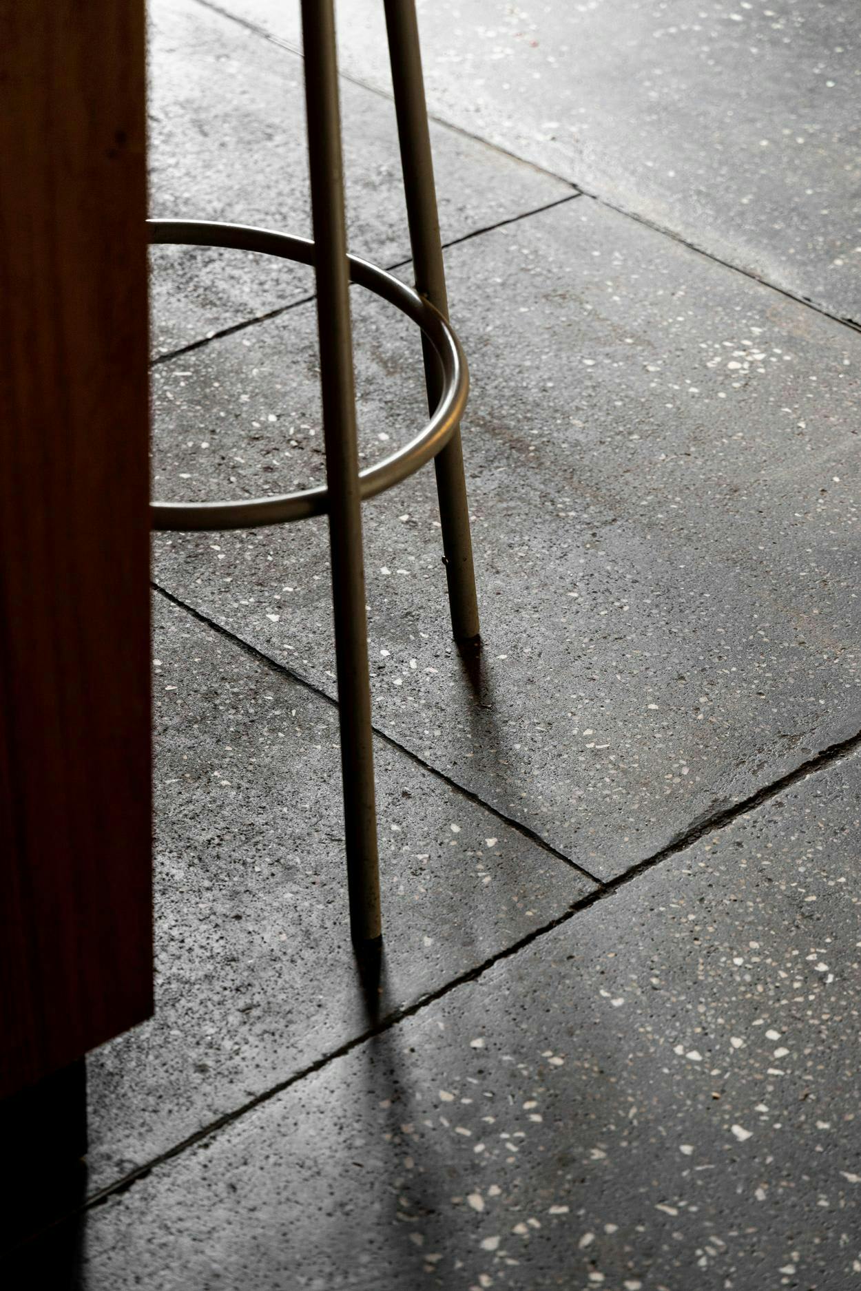 A chair is placed on a tiled floor, with a metal pole sticking out of it.