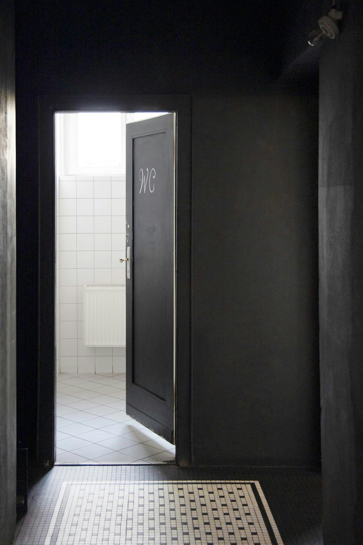 The image features a black doorway with a sign that reads "Bathroom."