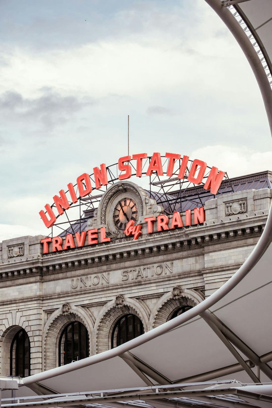 a train station with a clock on the top of it's roof and a sign that says union station travel and train