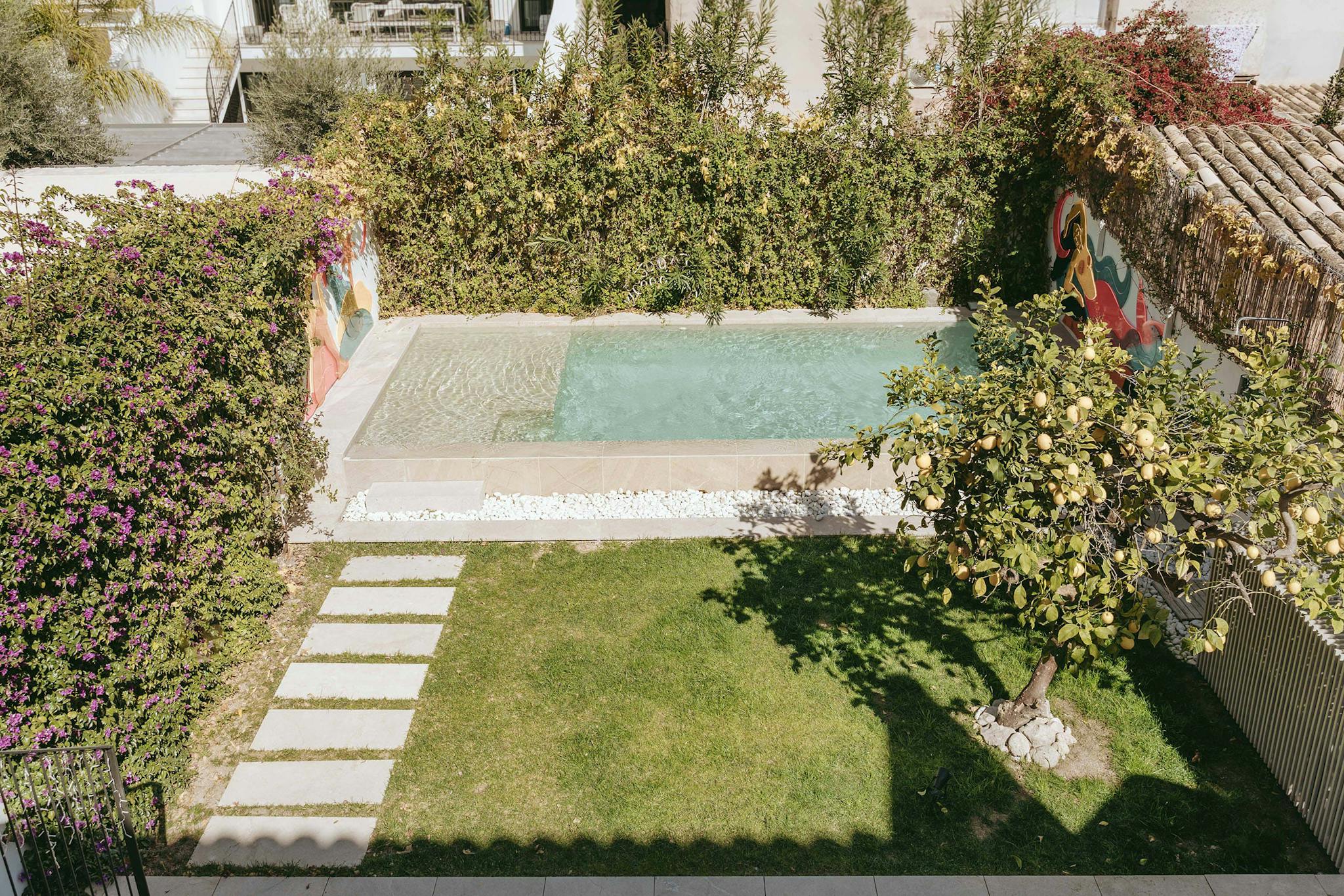 The image features a large, well-maintained backyard with a swimming pool, a patio, a garden, and a house.
