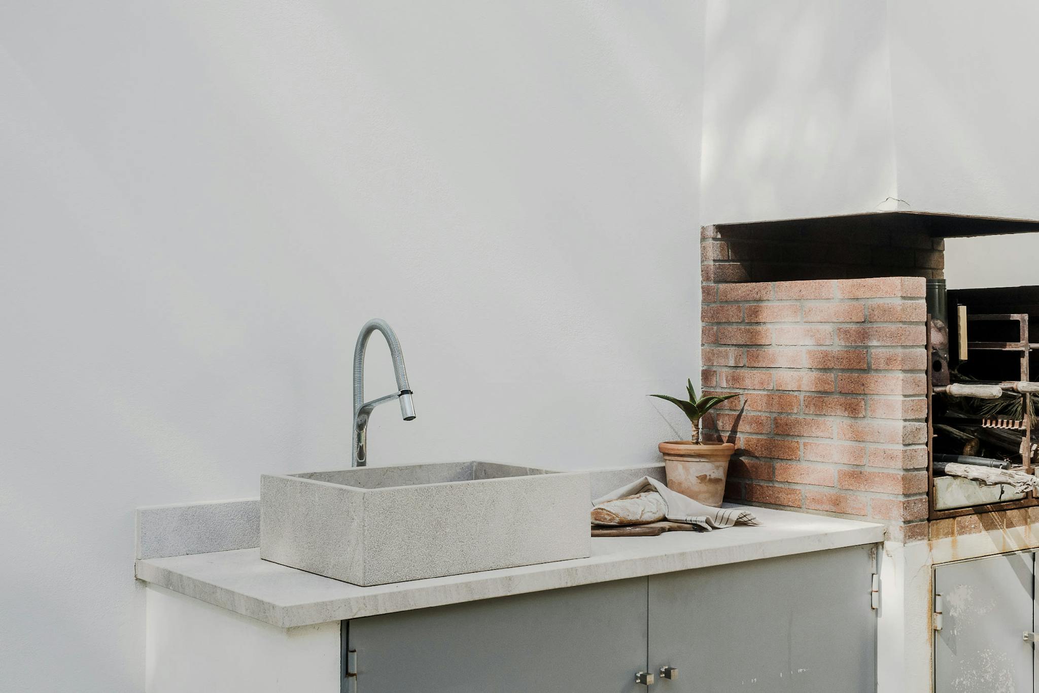 The image features a modern kitchen with a large sink, a stainless steel sink, and a brick oven.